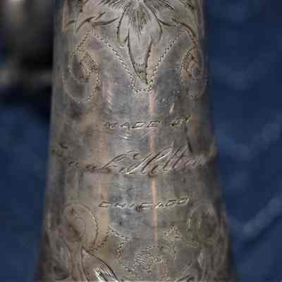 The "MADE BY FRANK HOLTON CO. CHICAGO" inscription near the bell. There are floral designs that surround it.