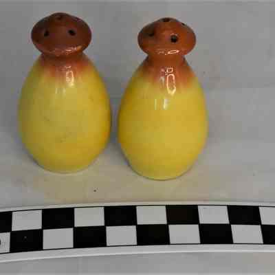 Other side and size comparison of yellow and orange salt & pepper shakers.