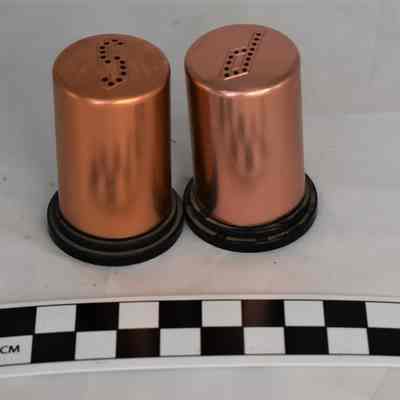 Back and size comparison of copper salt and pepper shakers.
