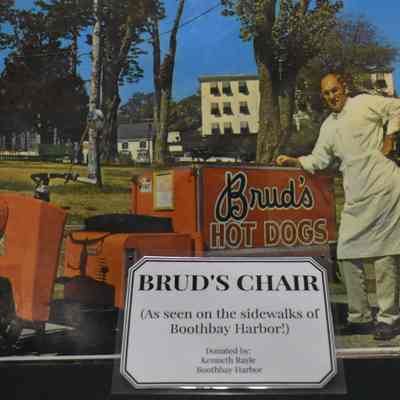 A picture of Brud next to his 1964 Cushman Truckster on the sidewalks of Boothbay Harbor, ME, ca. 1960s or 1970s.