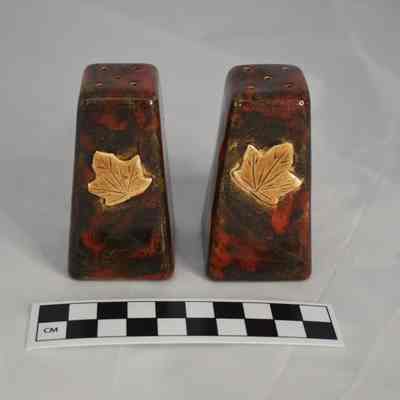 Back and size comparison of the salt and pepper shakers with a maple leaf on the back.