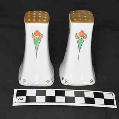 Back and size comparison of the white salt and pepper shakers with a floral design.