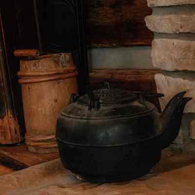 Cast iron kettle wooden bucket next to fireplace inside log cabin