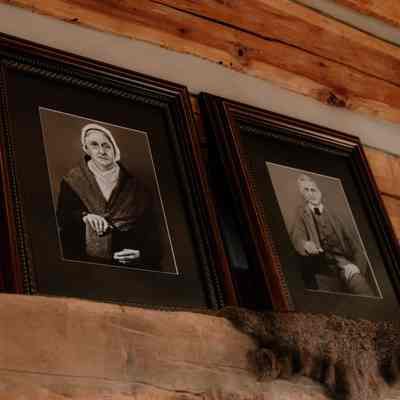 Portraits of Fannie and Nicholas Barker on top of fireplace mantle inside cabin