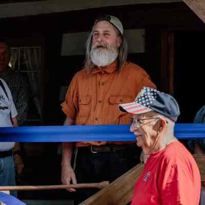 Cabin Master Michael Bailey speaking 1835 Barker Family Log Cabin front porch before ribbon cutting