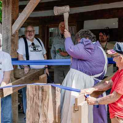 Diana Peyton chopping the ribbon for the Ribbon Cutting of the 1835 Barker Family Log Cabin