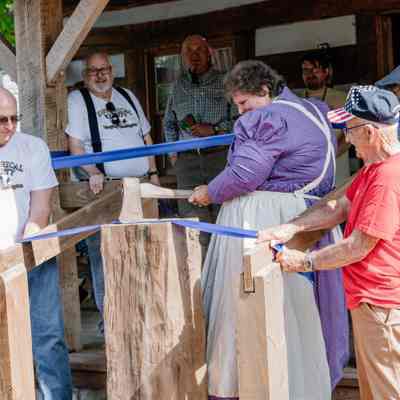 Diana Peyton chopping the ribbon for the Ribbon Cutting of the 1835 Barker Family Log Cabin