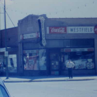 Westfield Pharmacy and Daugherty Super Regal Market with young man standing in front