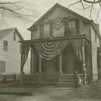 Marshall-Schmidt Album: Child With Flag in Front of House with Patriotic Bunting