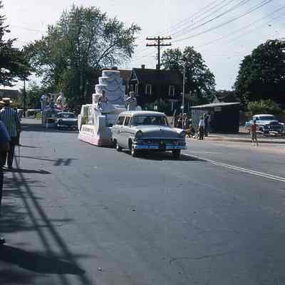 Suburban Dessert Shoppe 100th Anniversary Birthday Cake Float followed by the Chamber of Commerce Centennial Queen Float.