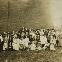 Group photograph of people in front of a brick building, c. 1905