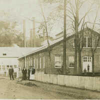 Diamond Mill with People Standing in Front of Brick Building