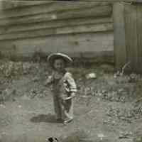 Marshall-Schmidt Album: Young Child in a Yard Wearing a Straw Hat