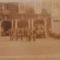 Fire Department: Photograph of many firefighters standing beside a firetruck outside the station