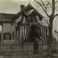 Marshall-Schmidt Album: Frank Marshall Standing Outside House Draped with Flags & Bunting