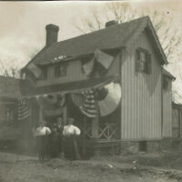 Marshall-Schmidt Album: Family Standing Outside Home Decorated with Bunting, c. 1907