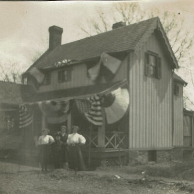 Marshall-Schmidt Album: Family Standing Outside Home Decorated with Bunting, c. 1907