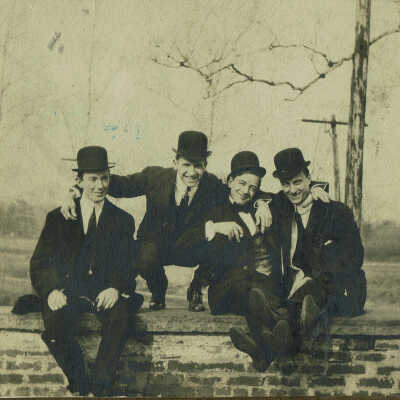 Four Men Seated on Brick Wall, c. 1900