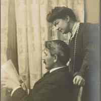 Snow: Ritch Photograph of Man Reading with Woman Standing Behind