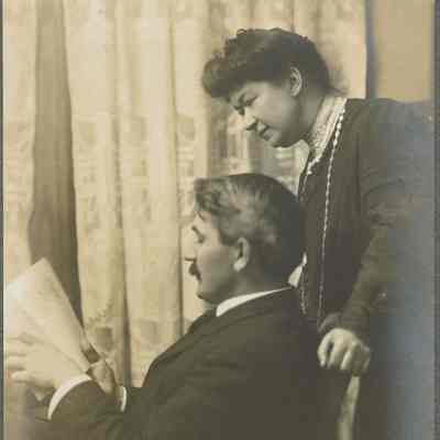 Snow: Ritch Photograph of Man Reading with Woman Standing Behind
