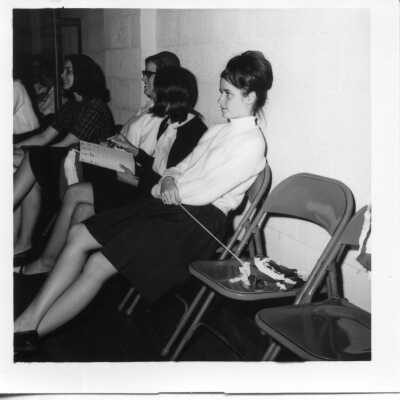 Student sitting on a chair holding a pom pom in 1965