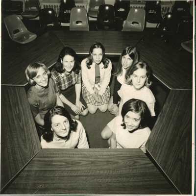 Students in 1972 huddle together inside some desks.