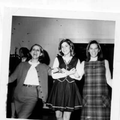 Three girls arm in arm not in uniform.