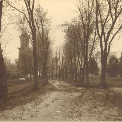 Picture of tree-lined path with bell tower visible in distance. Assume this is early picture of Ward-Belmont campus.