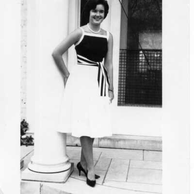 Student standing at the front door of Souby Hall in a black and white dress.
