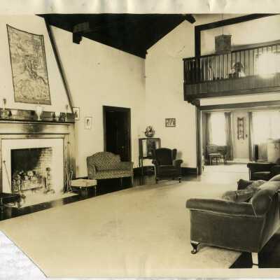 Club Village, interior, fireplace, sofas, balcony. Trophies visible on mantle.