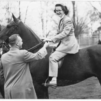 Woman on horse, next to standing man (date unknown)