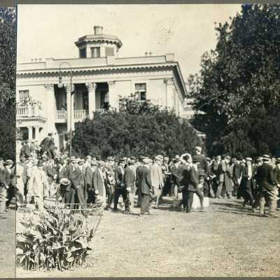 Belmont College for Young Women, circa 1910. A crowd of men in suits and hats walking on the campus lawn.
