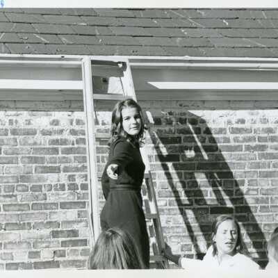 Elaine Reynolds, class of 1972 leans a ladder against the Senior House.