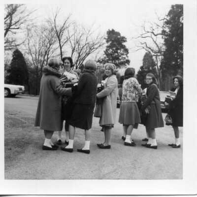 Students standing outside holding all of their books in 1963.