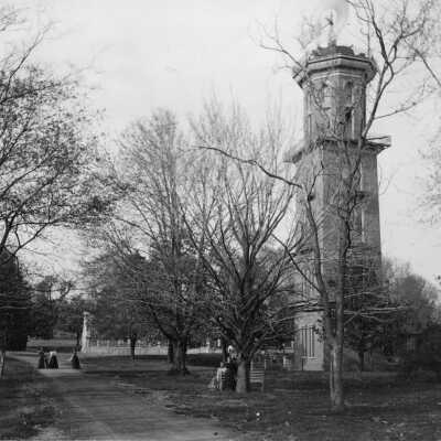Picture of the water tower and greenhouse with several people visible. Possibly dating back to Belmont College for Young Women.