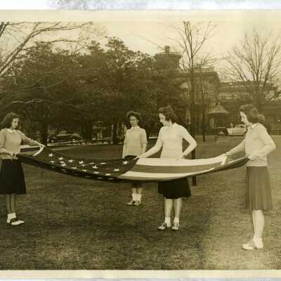Students folding the American flag on the lawn.