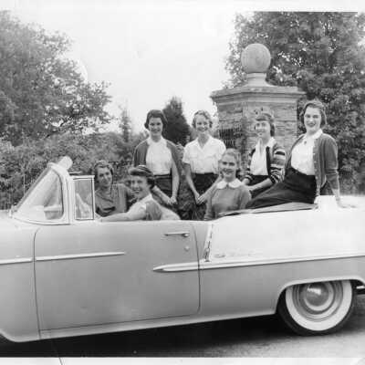 Class of 1954 Seniors in a car at the school entrance wearing their senior beanies.