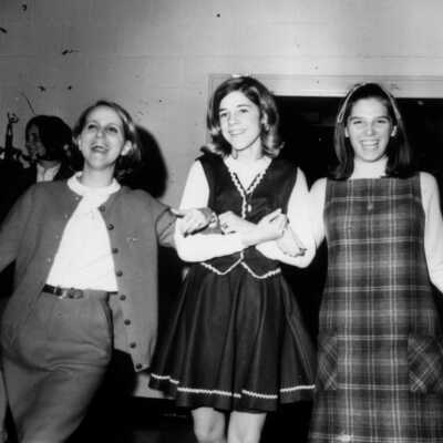 Three students, arm in arm but not in uniform.