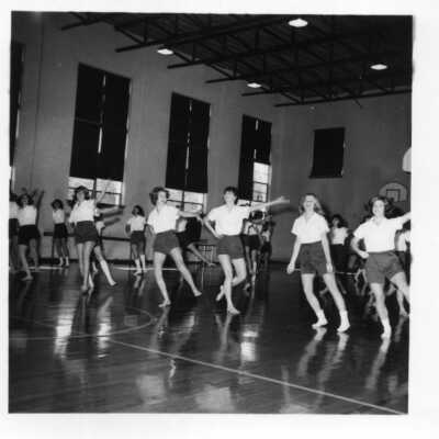 Students in PE class in the Bullard gym wearing white shirts and dark shorts circa 1960's.