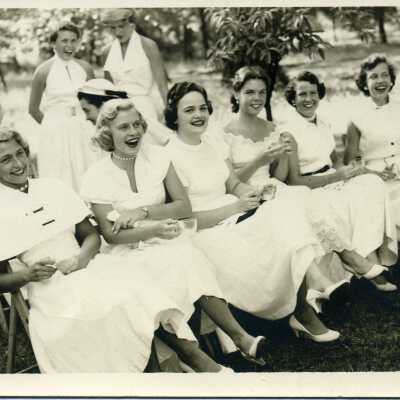 Young ladies in white dresses, sitting on the lawn