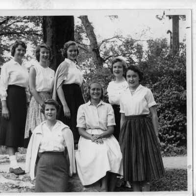 Pat Moran with students outside by tree. Students are from the class of 1961