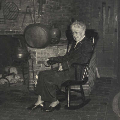 Anna Lincoln sitting in front of massive fireplace in the historic Lincoln house, Dennysville, Maine | c.1950