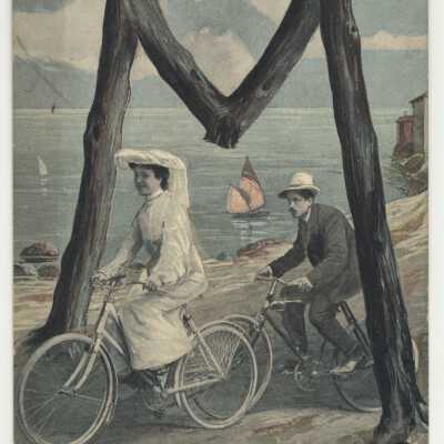 Postcard - Cyclists ride under letter M at beach