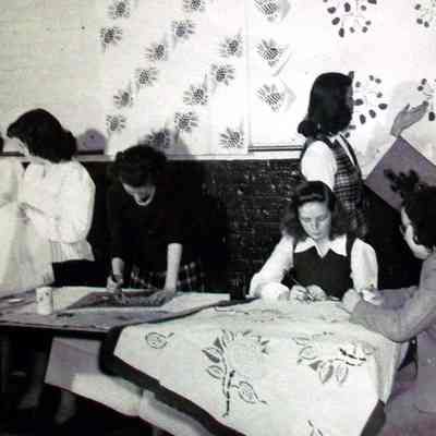 2009.59.8: In this photograph, women are stenciling a sheet with the same pattern.