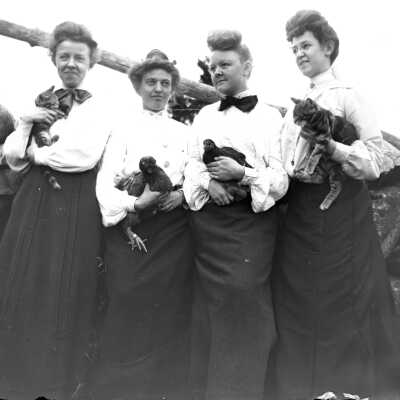 Four unidentified women holding cats and hens