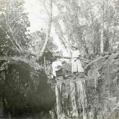 Two Unknown Women Standing at the Top of a Small Waterfall