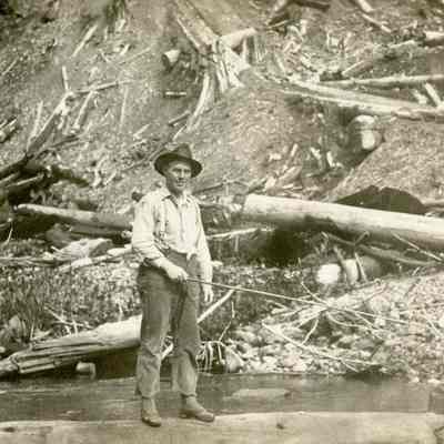 Unknown Man Standing on a Log in the Water