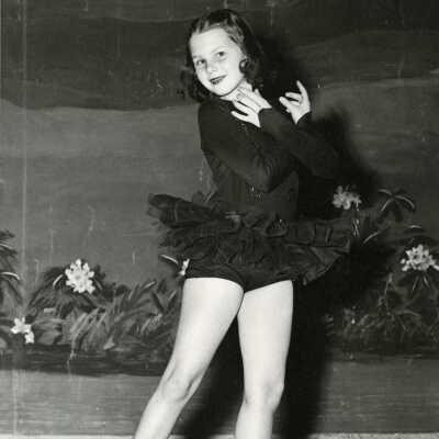 Girl in Ballet Pose wearing a Dark Tutu.