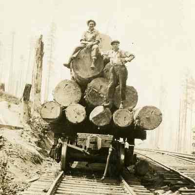 Two Unknown Men on Railroad Car with Logs