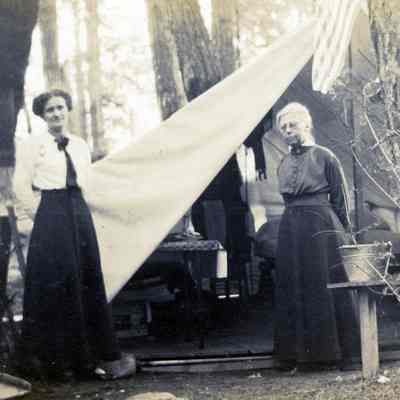 Two Women Standing Next to Tent